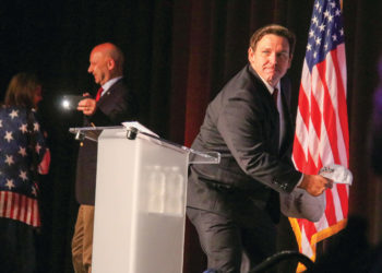 Florida Governor Ron DeSantis throws hats into the crowd of the Turning Point USA rally in Pittsburgh on Friday as Sen. Doug Mastriano takes a picture of him in the background.