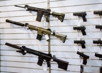Stock image of gun wall rack with rifles and pistol.