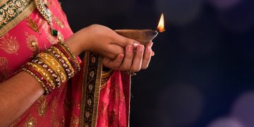 Stock image of woman holding oil lamp during Diwali, a Hindu festival.