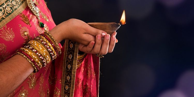 Stock image of woman holding oil lamp during Diwali, a Hindu festival.