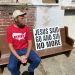 Damon Atkins sits on a bench outside his home in central Reading. A sign sits besides him with the words, "Jesus Said Go and Sin No More."
