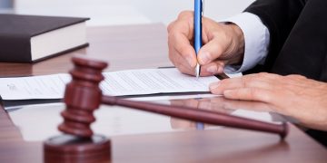 Stock image of judge writing on paper In courtroom.